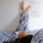 Personne allongée en pyjama, pieds contre le mur.