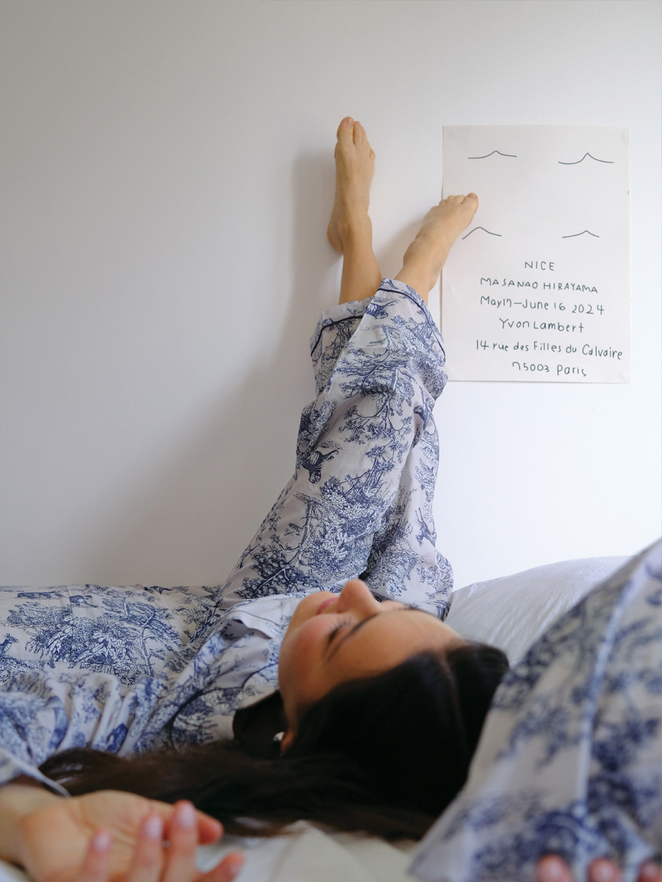 Personne allongée en pyjama, pieds contre le mur.