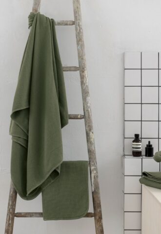 Serviette verte suspendue à une échelle en bois.