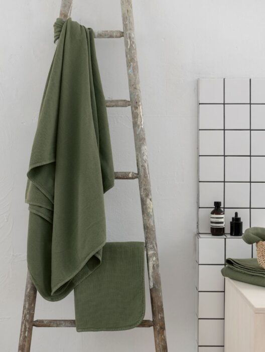 Serviette verte suspendue à une échelle en bois.