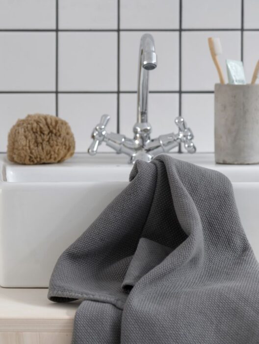 Lavabo avec serviette grise et accessoires.