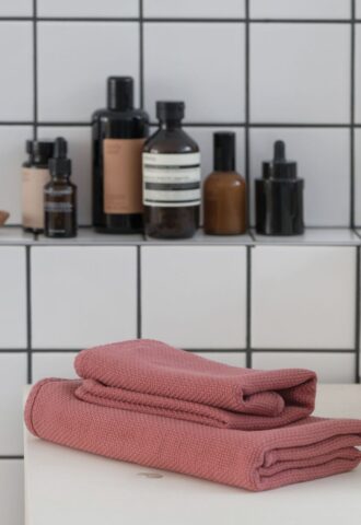 Serviettes roses et produits de bain sur étagère.