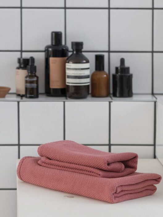 Serviettes roses et produits de bain sur étagère.