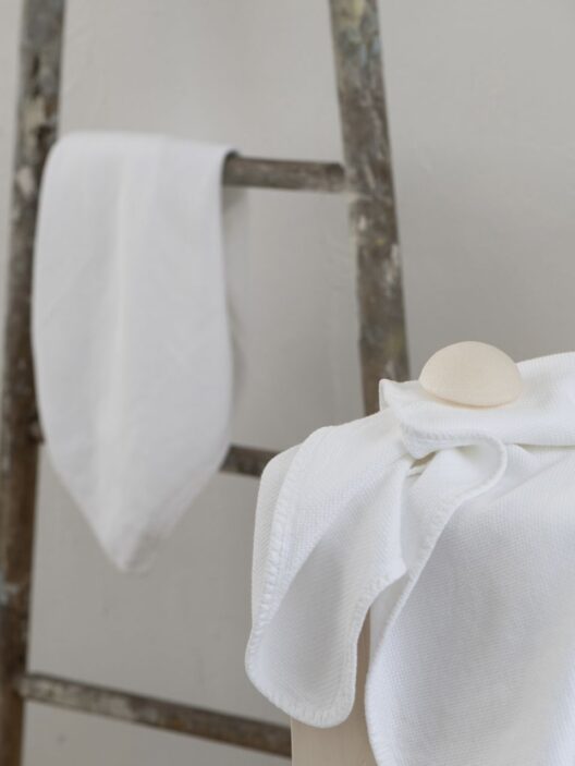 Serviettes blanches sur échelle en bois.
