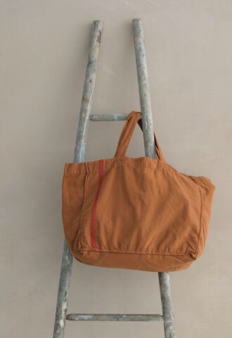 Sac orange sur une échelle en bois.
