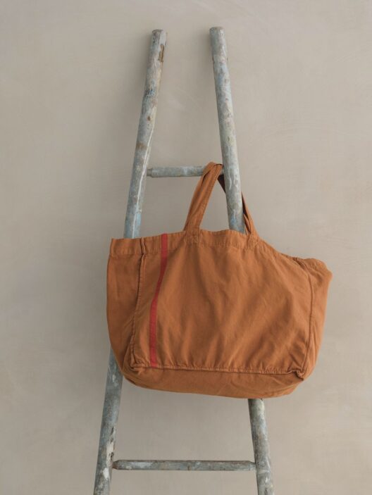 Sac orange sur une échelle en bois.