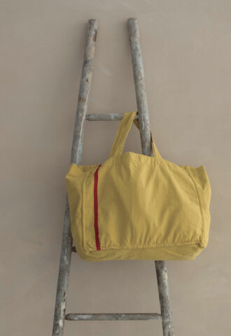 Sac jaune posé sur une échelle grise.