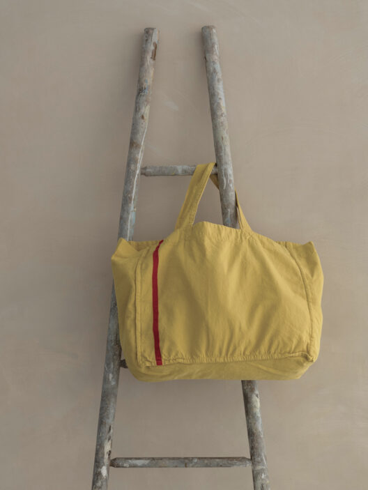 Sac jaune posé sur une échelle grise.