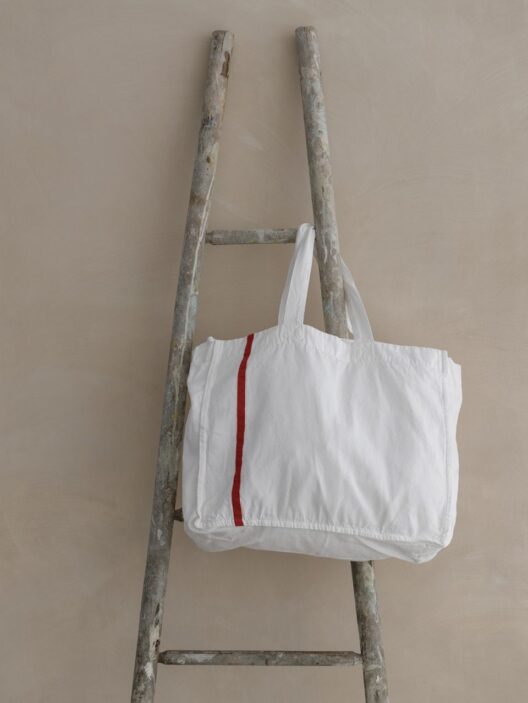 Sac blanc suspendu à une échelle en bois.