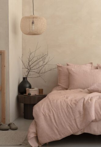 Chambre beige avec lit et lampe suspendue.