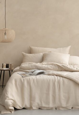 Lit beige avec livre et lampe suspendue.