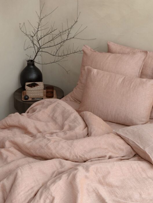 Chambre avec literie beige et vase décoratif.