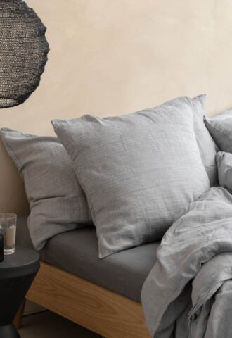 Lit gris avec oreillers et couverture.