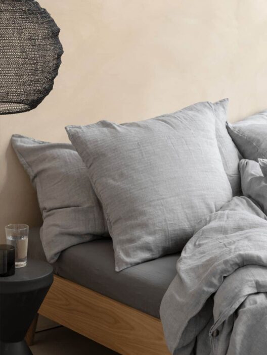 Lit gris avec oreillers et couverture.