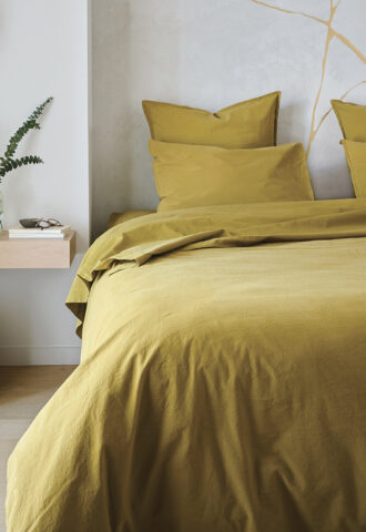 Chambre avec lit et décoration minimaliste jaune.