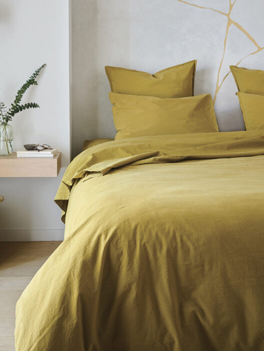 Chambre avec lit et décoration minimaliste jaune.