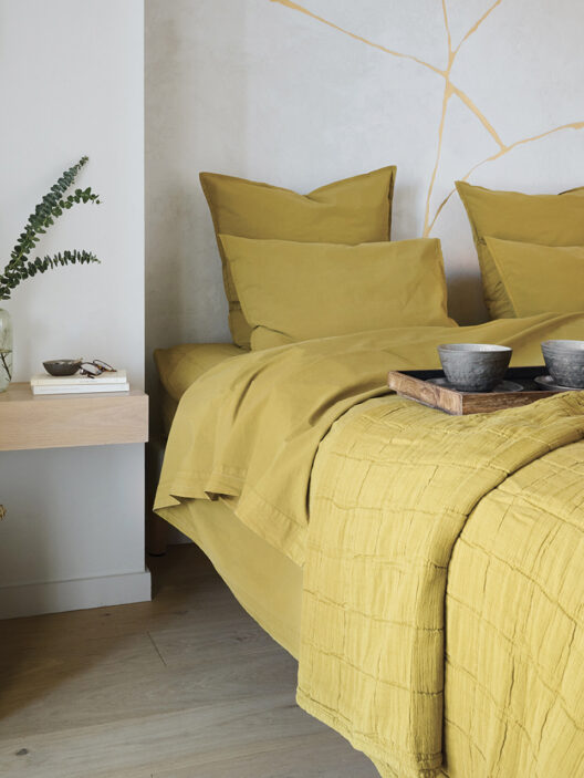 Chambre moderne avec literie jaune moutarde.