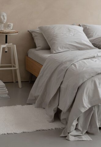 Lit avec draps gris et table de chevet.