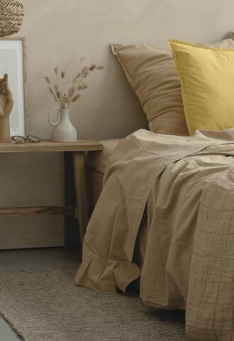Chambre minimaliste avec décorations naturelles et oreiller jaune.