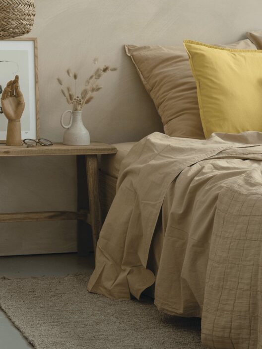 Chambre minimaliste avec décorations naturelles et oreiller jaune.