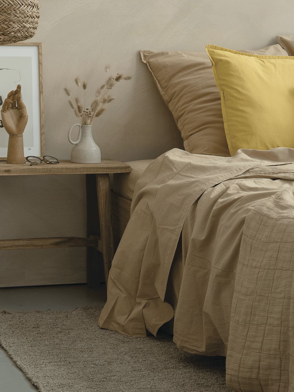 Chambre minimaliste avec décorations naturelles et oreiller jaune.