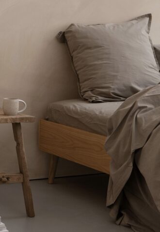 Lit avec literie beige et table en bois