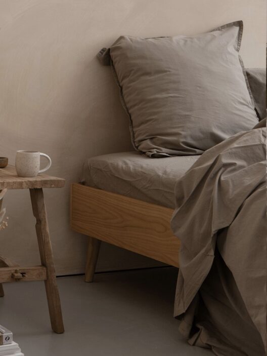 Lit avec literie beige et table en bois