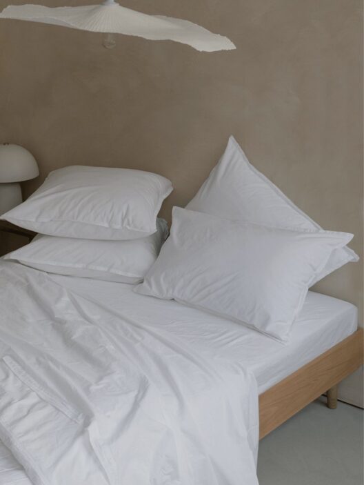 Lit avec oreillers et draps blancs.
