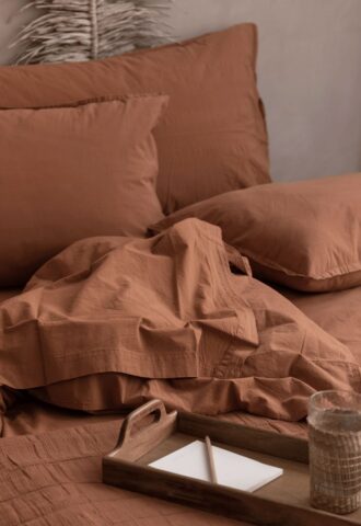 Lit marron avec plateau et verre d'eau.