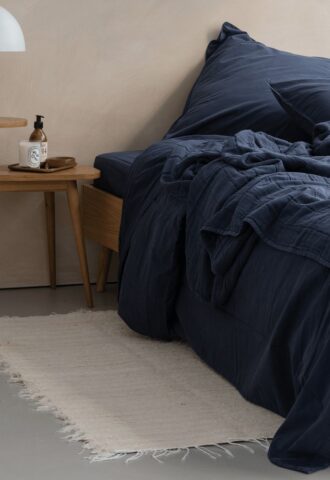 Lit avec draps bleus et table de chevet.