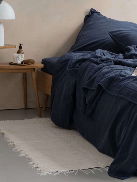 Lit avec draps bleus et table de chevet.