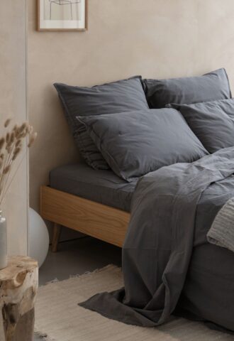 Chambre minimaliste avec lit gris et décor naturel.