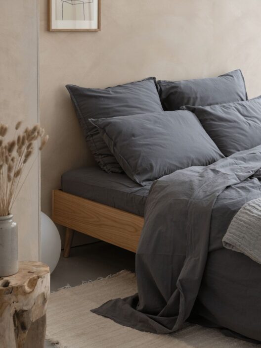 Chambre minimaliste avec lit gris et décor naturel.