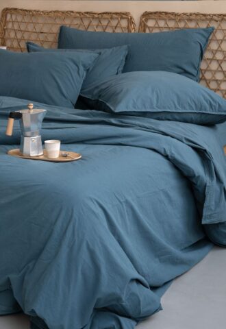 Lit avec draps bleus et cafetière.