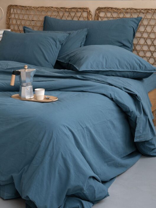 Lit avec draps bleus et cafetière.