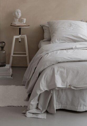 Chambre minimaliste avec lit gris et décoration moderne.