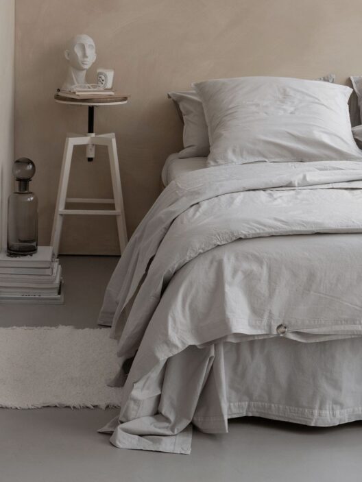 Chambre minimaliste avec lit gris et décoration moderne.