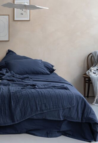 Chambre avec lit bleu et décor minimaliste.