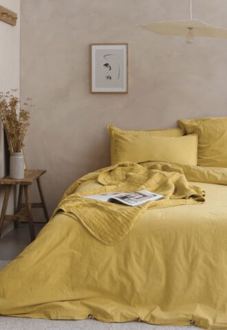 Chambre avec literie jaune et décoration minimaliste.