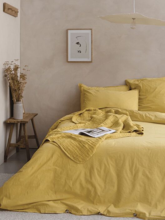 Chambre avec literie jaune et décoration minimaliste.