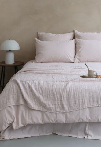 Lit avec draps et lampe sur table.