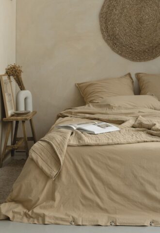 Chambre minimaliste avec lit beige et livre ouvert.