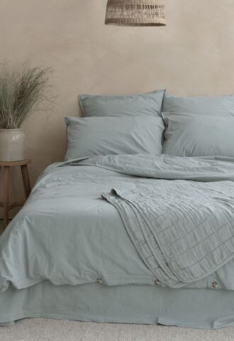 Lit avec linge bleu dans une chambre apaisante.