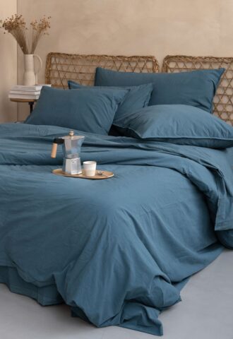 Lit avec draps bleu et plateau café.