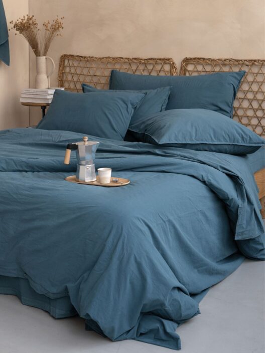 Lit avec draps bleu et plateau café.