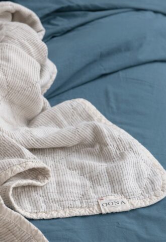 Couverture rayée blanche sur drap bleu.