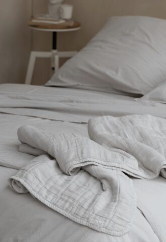 Lit avec draps blancs et table de chevet