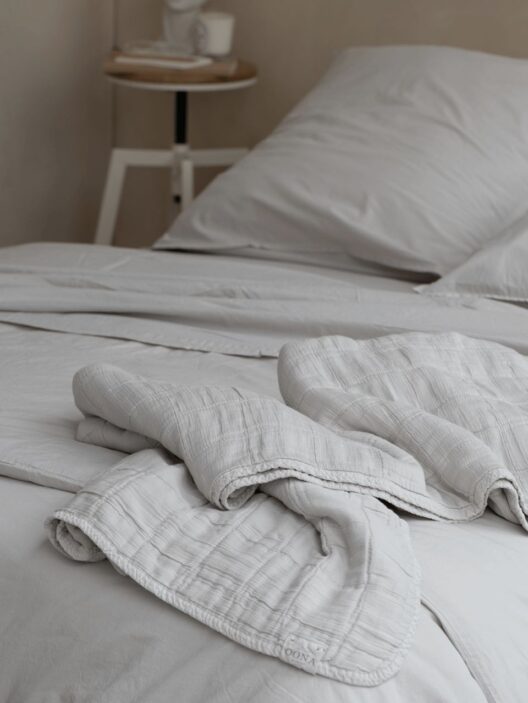 Lit avec draps blancs et table de chevet