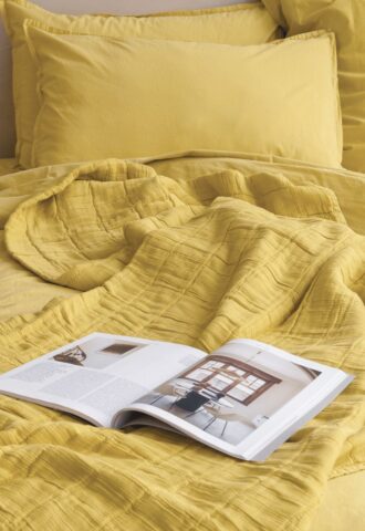 Lit jaune avec magazine ouvert.