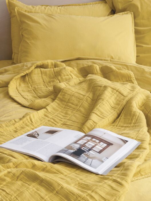 Lit jaune avec magazine ouvert.